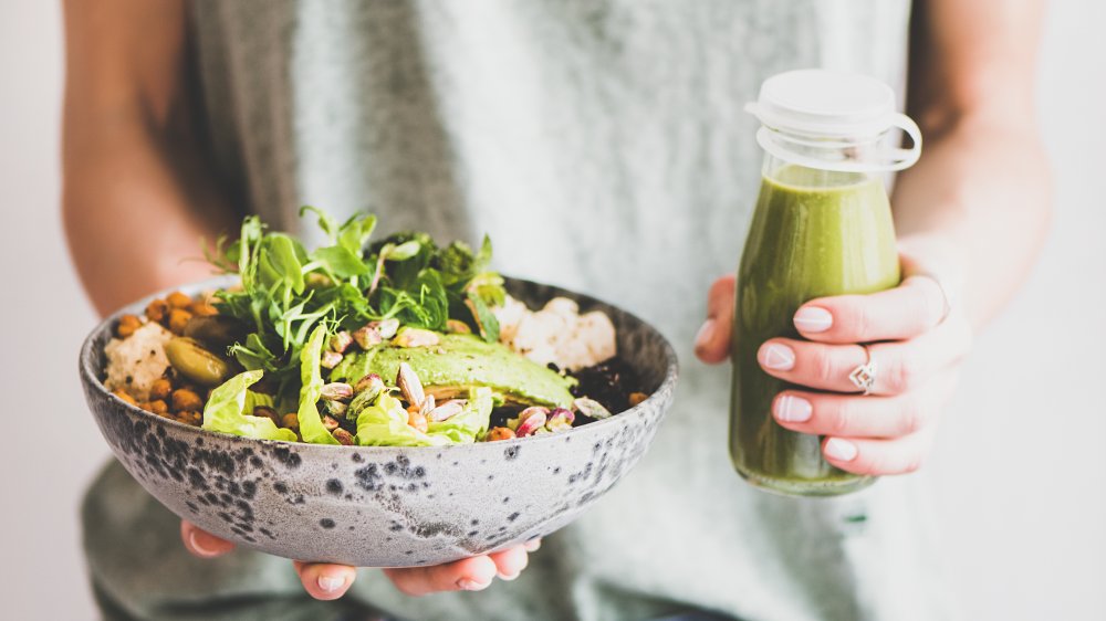 Woman holding reen juice and salad