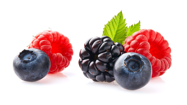 raspberries, blueberries, and one blackberry against white background