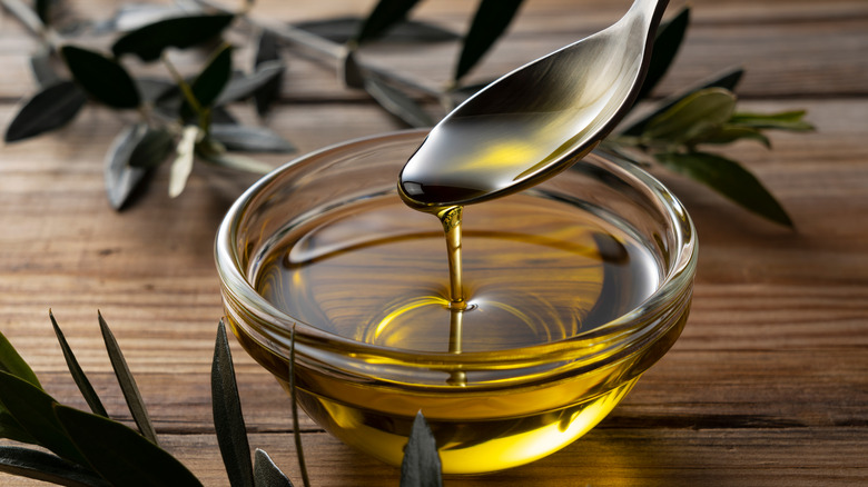 spooning olive oil into a bowl