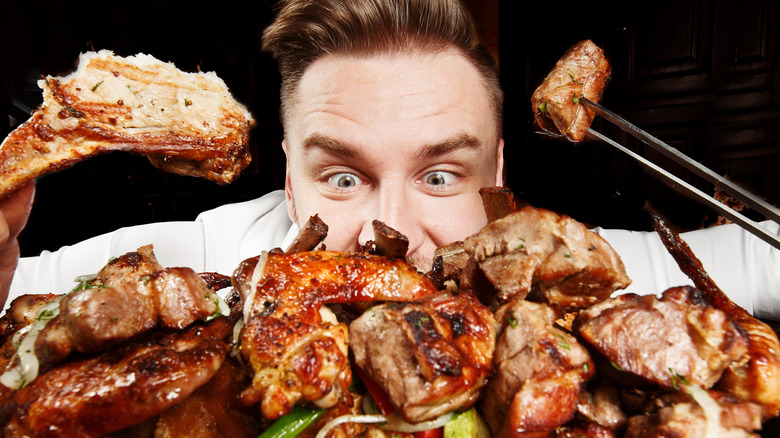 man eyeing many pieces of chicken in front of him