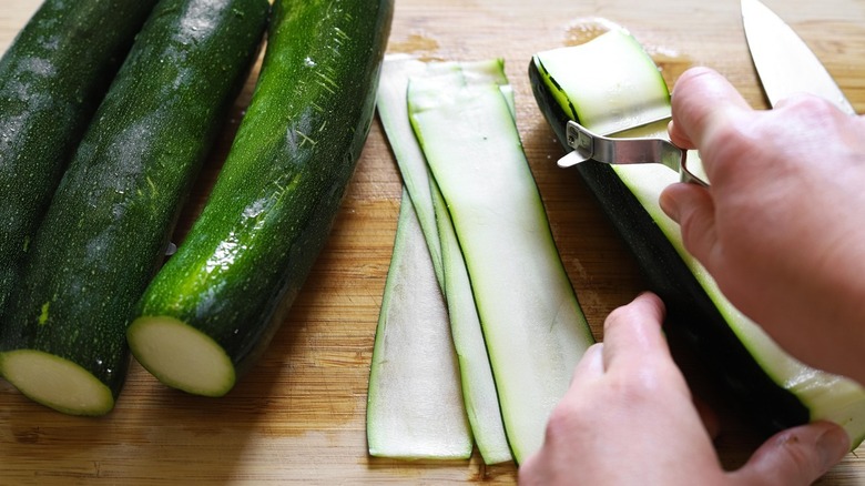 fresh green zucchini being sliced thinly