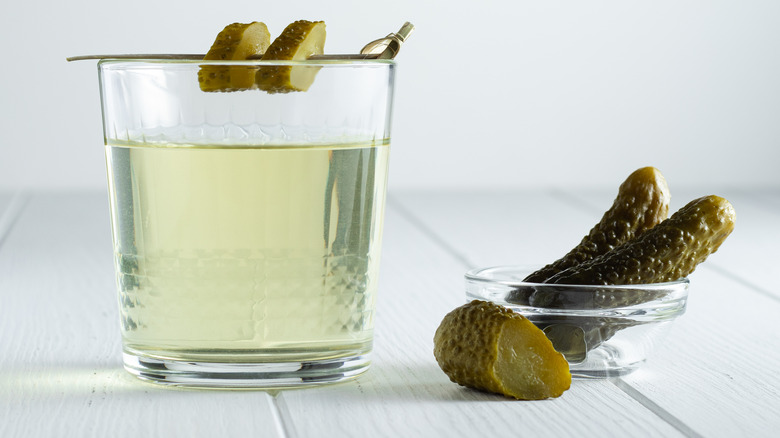 Pickles next to glass of pickle brine