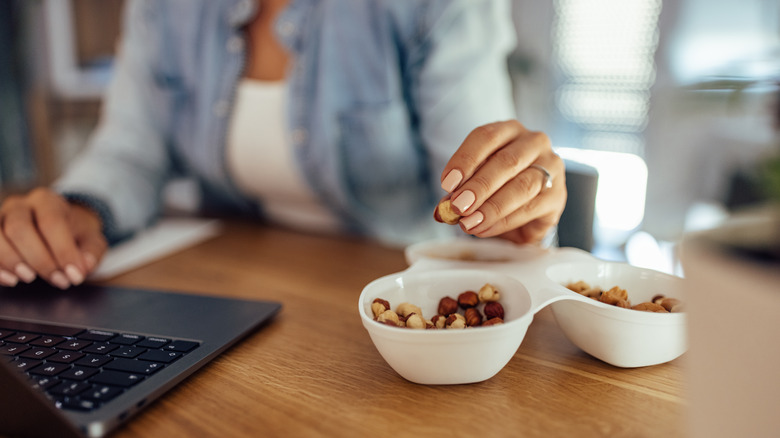 Woman at desk snacking on nuts