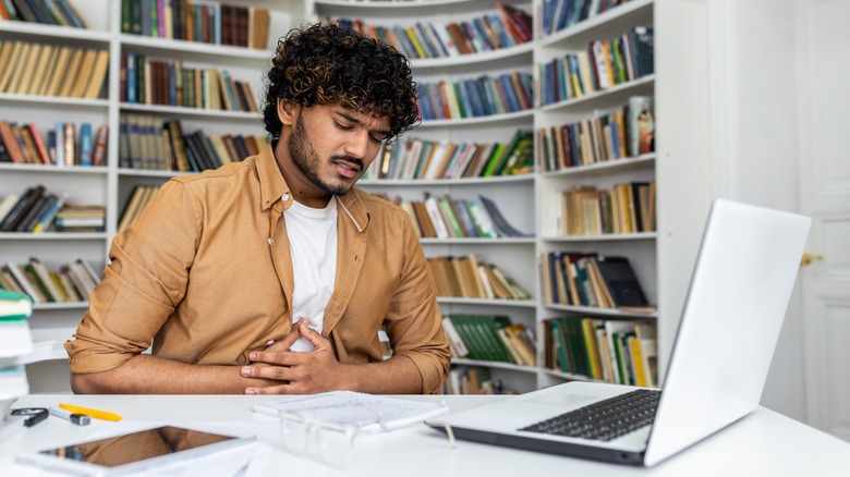 Man with stomach pain sitting at desk