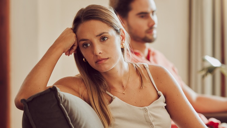 man and woman sitting on couch upset
