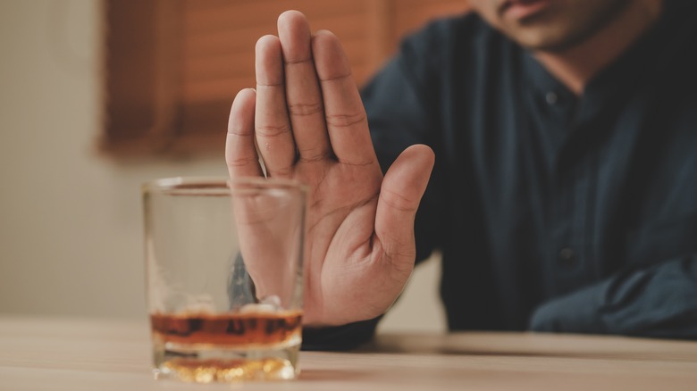 man holding up hand refusing alcohol