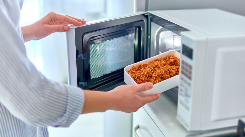 woman microwaving container of leftovers
