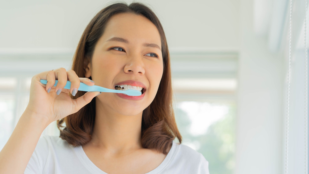 Woman in a white shirt brushing her teeth