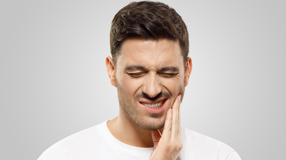Man holding the side of his face because of tooth pain