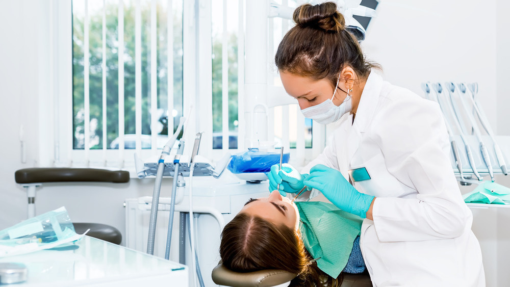 Dentist examining female patient's teeth