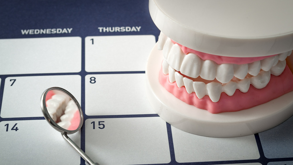 A pair of fake teeth and a dental mirror sitting on a calendar