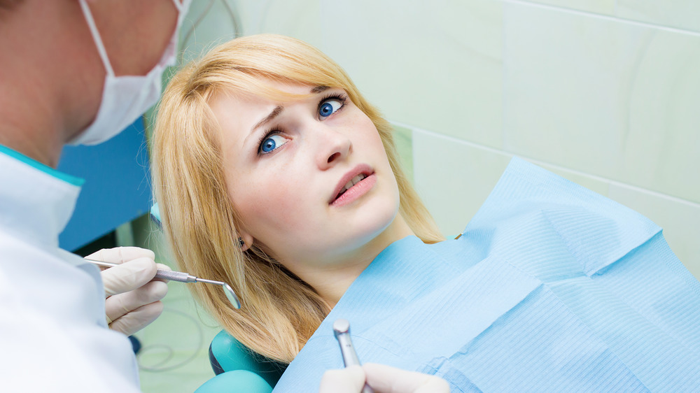 Afraid woman in a dentist chair looking up at her dentist