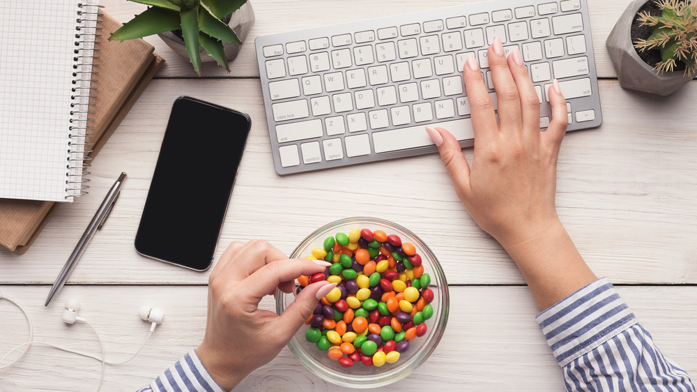 woman eating skittles at desk