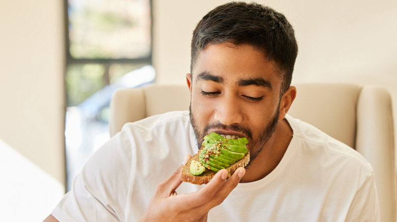 A man at his kitchen table eating avocado toast