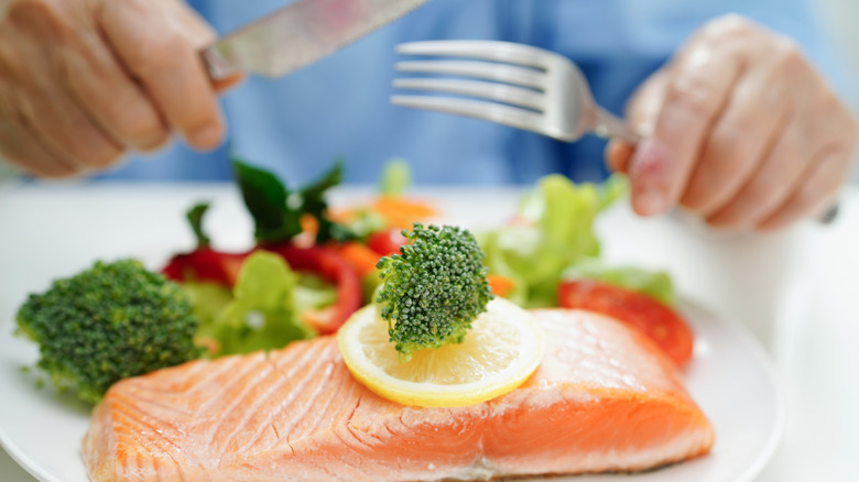 A man eating salmon with a knife and fork