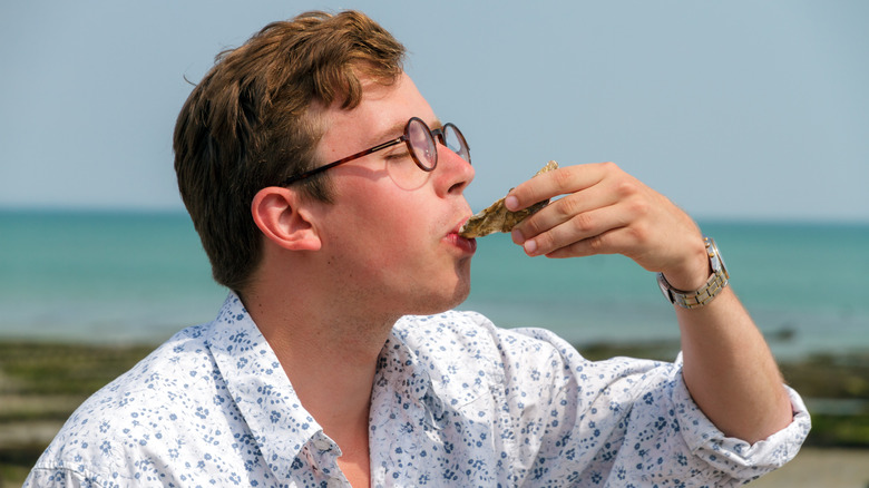 A man eating an oyster by the ocean