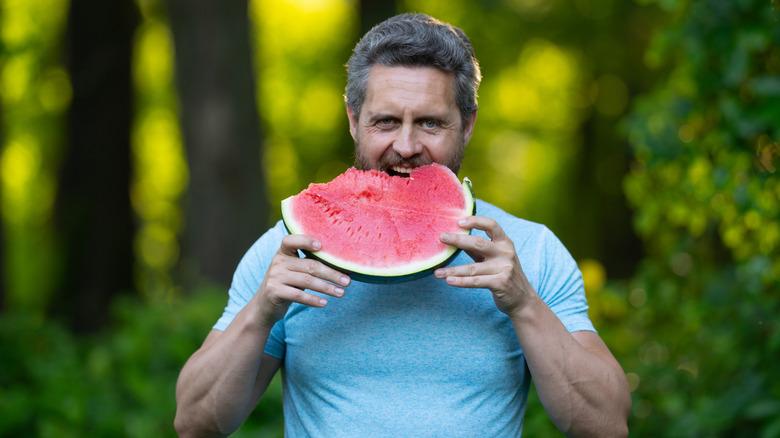 A man eating a slice of watermelon outside in the summer