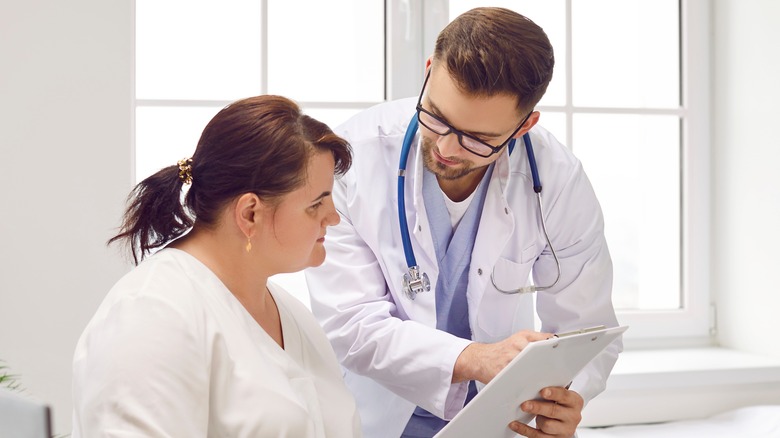 A doctor showing a woman information on a clipboard