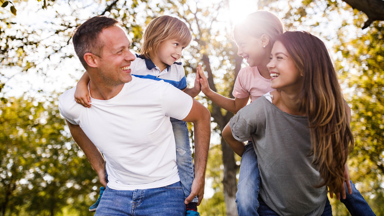 mom and dad holding kids and smiling outside