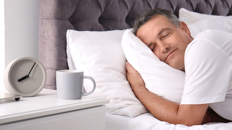 Man cradling pillow asleep in bed