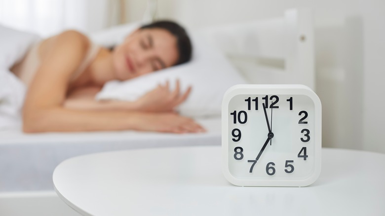 Clock next to sleeping woman