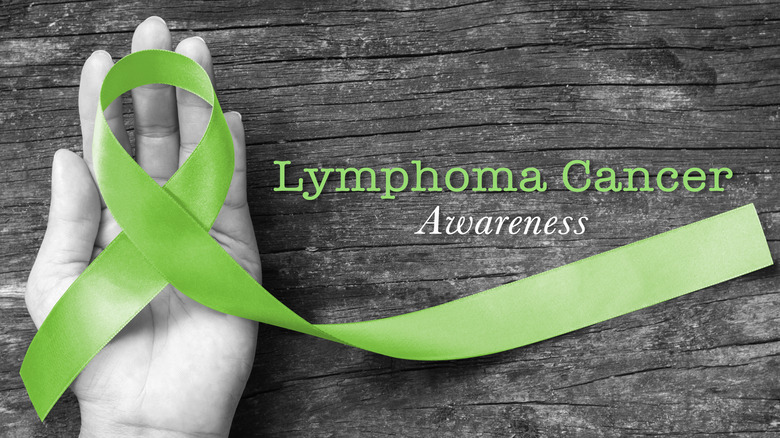 Black and white image of a hand holding a green ribbon with words reading "Lymphoma Cancer Awareness"
