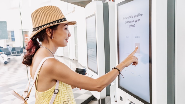 woman ordering fast food at a touchscreen kiosk