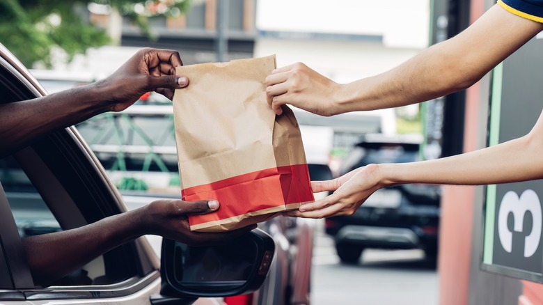 fast-food worker handing customer a bag of food