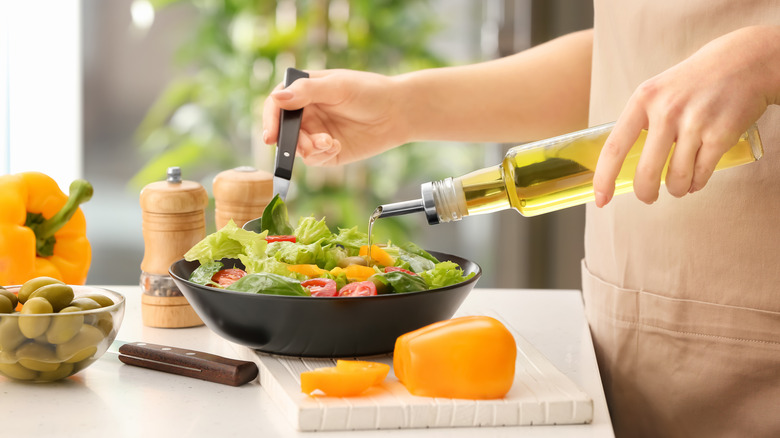 pouring salad dressing on a salad