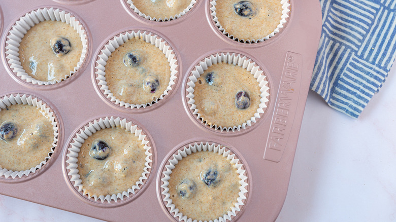 Scooping blueberry muffin batter into baking tray