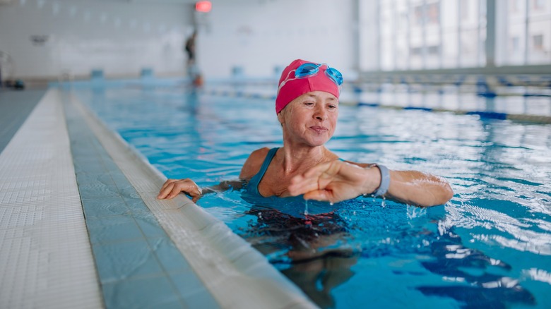 Older woman looking at smartwatch in pool