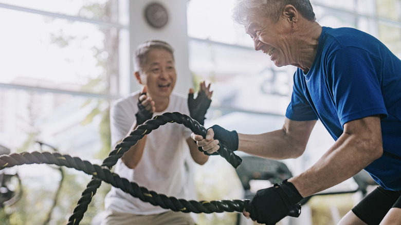 older adult doing HIIT with battle ropes