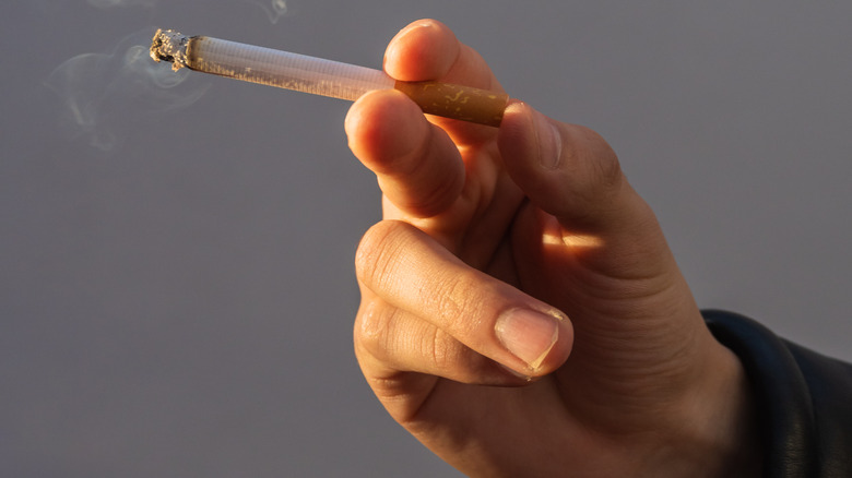 Close up of a hand holding a lit cigarette