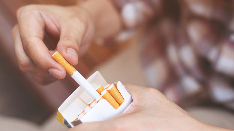 hand removing cigarette from the pack