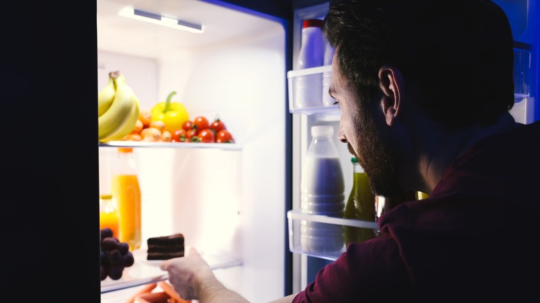 Man reaching in fridge for cake