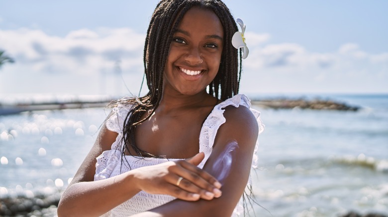 Young woman putting on sunscreen in paradise