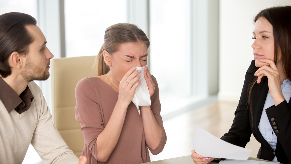 group of people with sick lady sneezing