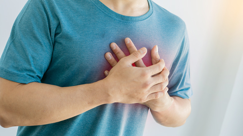 male clasps hands over chest in pain