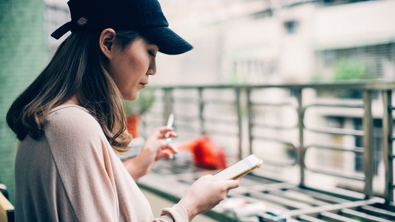 woman smokes cigarette while on phone