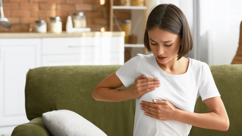 woman holds breast in pain