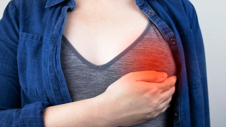 a woman holds her breast in pain