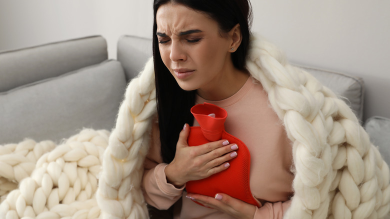 woman in pain holds warm compress to breast