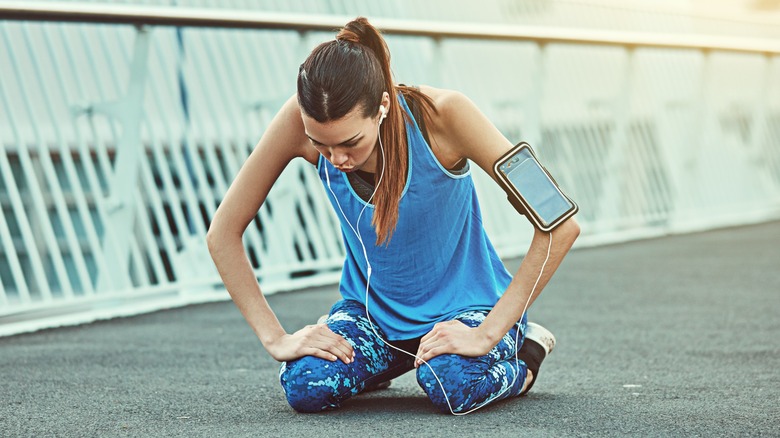 young woman athlete on her knees catching her breath