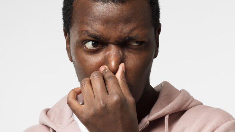 Man pinching his nose to avoid bad smell