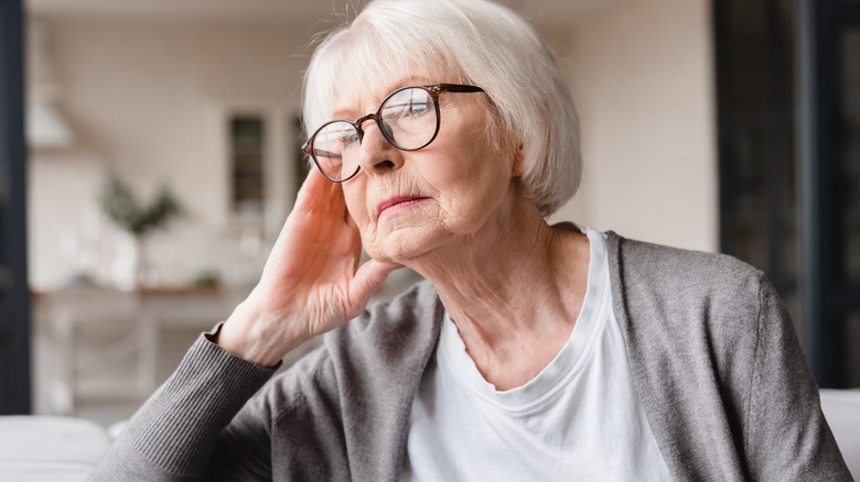 tired elderly woman looking outside