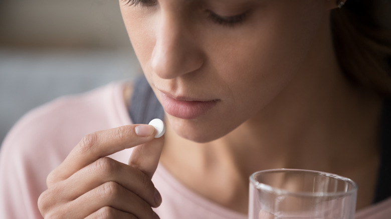 a woman taking a pill with water