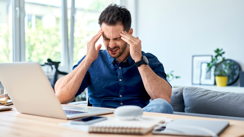 Man with a migraine holding his head in pain 