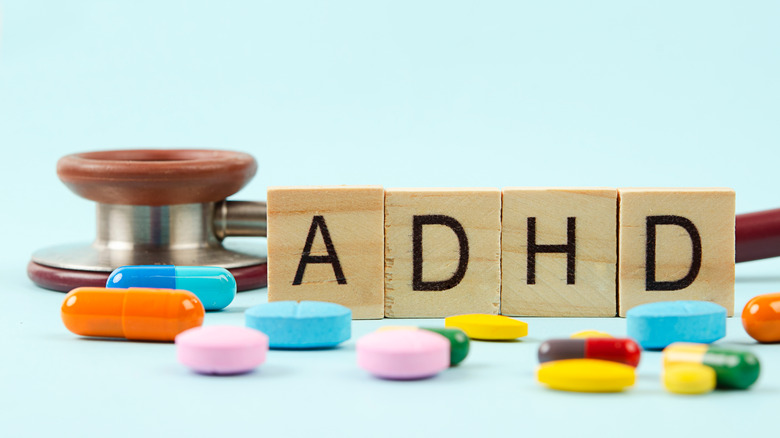 wooden blocks spelling ADHD alongside colorful pills