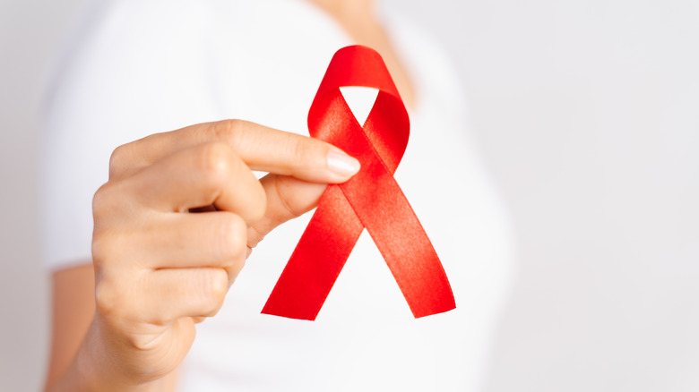 red AIDS ribbon held with hand
