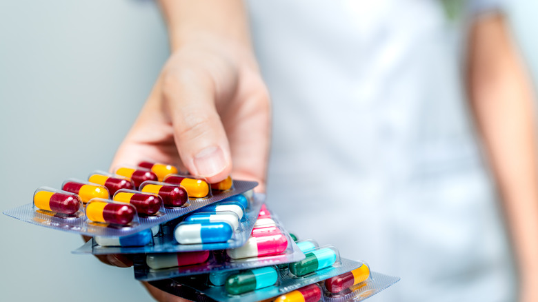 woman holding packages of colorful pills on a blue background